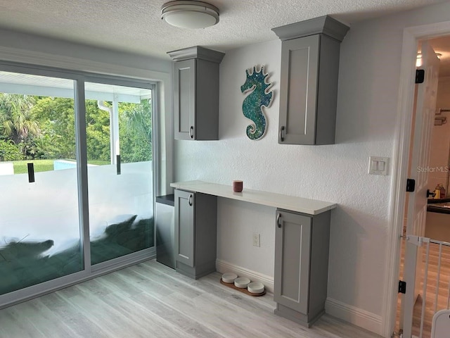 kitchen featuring gray cabinetry, a textured ceiling, and light hardwood / wood-style flooring