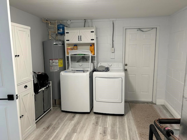 laundry room featuring cabinets, washing machine and dryer, water heater, and light wood-type flooring