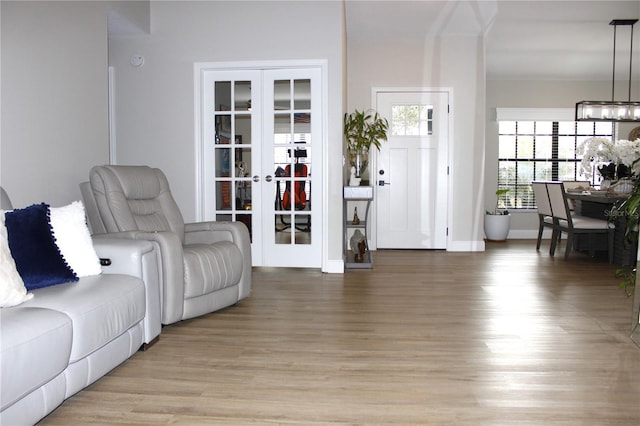 living room featuring french doors, a notable chandelier, and light hardwood / wood-style floors