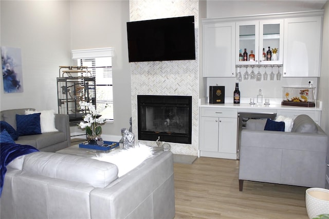 living room with light hardwood / wood-style floors, indoor bar, and a fireplace