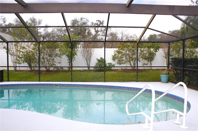 view of swimming pool featuring a lanai and a lawn