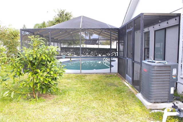 view of pool with a lanai, central AC unit, and a yard