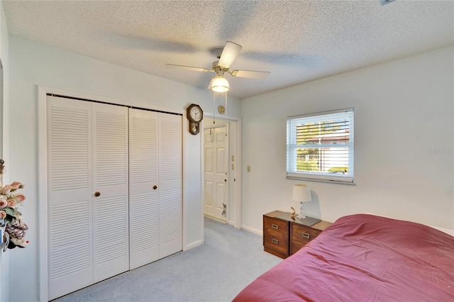 carpeted bedroom with a closet, ceiling fan, and a textured ceiling