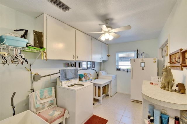 washroom with ceiling fan, cabinets, washing machine and dryer, and a textured ceiling