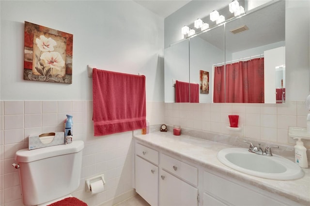 bathroom featuring tile walls, curtained shower, vanity, and toilet