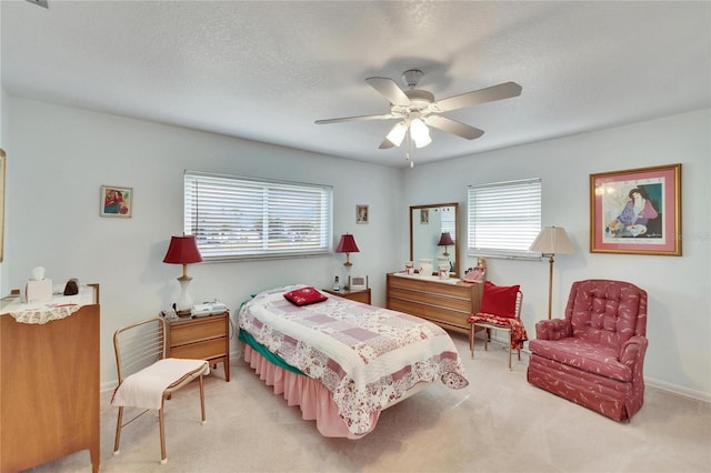 bedroom with a textured ceiling, ceiling fan, and light colored carpet