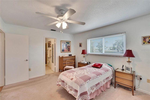 bedroom featuring ceiling fan, light colored carpet, and ensuite bathroom