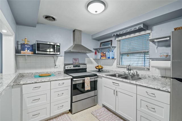 kitchen with white cabinets, stainless steel appliances, decorative backsplash, sink, and wall chimney range hood