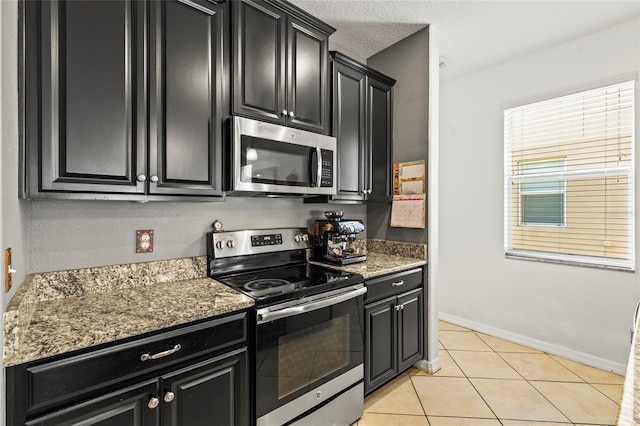 kitchen with dark stone counters, stainless steel appliances, and light tile patterned floors