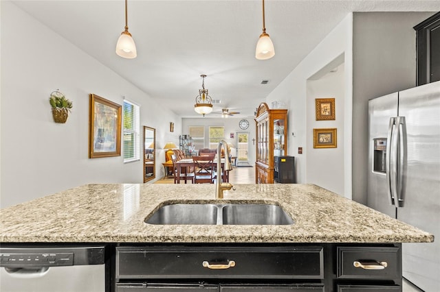 kitchen featuring decorative light fixtures, a center island with sink, appliances with stainless steel finishes, and sink