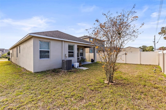 rear view of property with central AC and a lawn