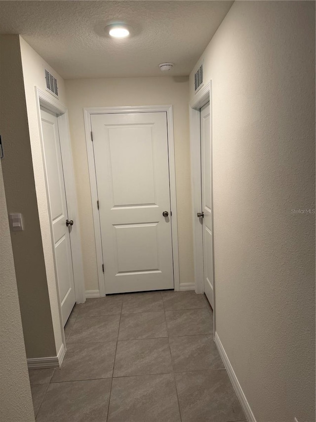 hallway featuring tile patterned flooring and a textured ceiling