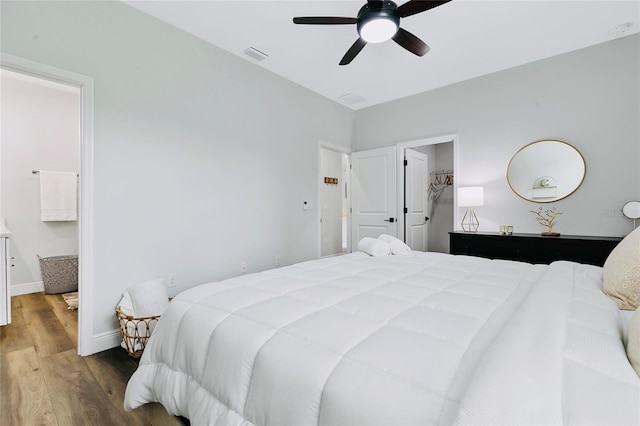 bedroom with ceiling fan, wood-type flooring, and ensuite bath