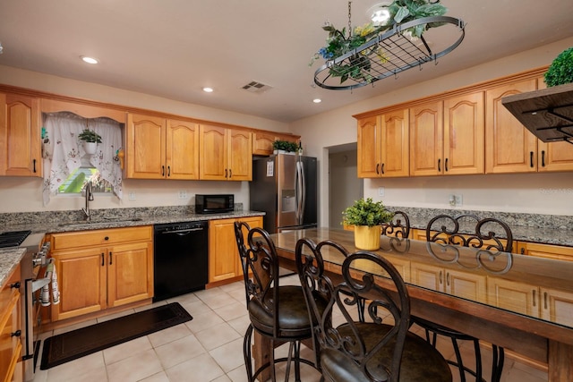 kitchen with sink, light tile patterned floors, black appliances, and stone countertops