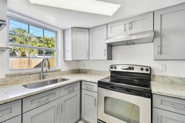 kitchen with light stone countertops, gray cabinets, stainless steel range with electric stovetop, and sink