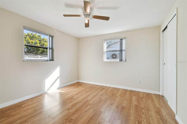 unfurnished bedroom with multiple windows, light wood-type flooring, a closet, and ceiling fan