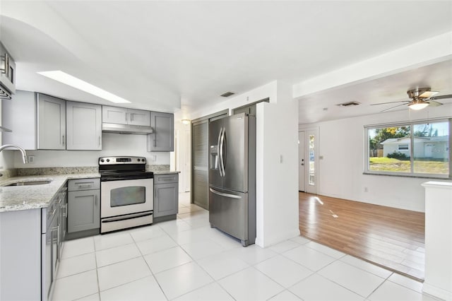 kitchen with stainless steel fridge, electric range oven, light stone counters, gray cabinetry, and sink