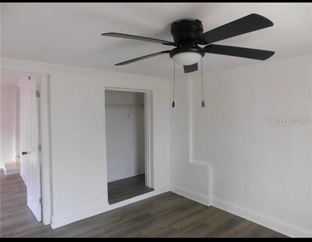 unfurnished bedroom with dark wood-type flooring, ceiling fan, a closet, and ornamental molding