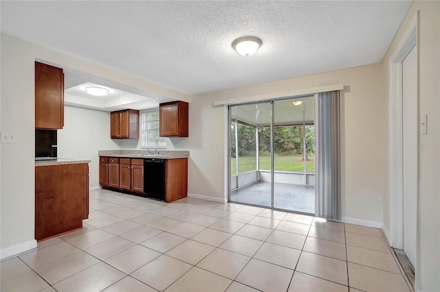 kitchen with a textured ceiling, a tray ceiling, sink, light tile patterned floors, and dishwasher