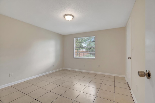 empty room featuring light tile patterned floors and a textured ceiling