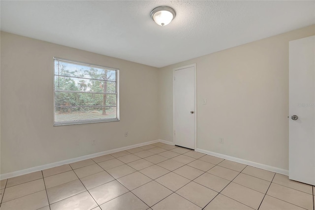 tiled empty room featuring a textured ceiling