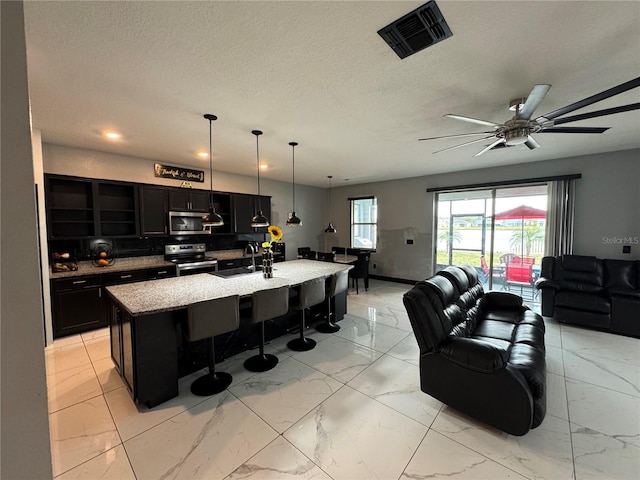 kitchen with stainless steel appliances, sink, hanging light fixtures, a breakfast bar, and a center island with sink