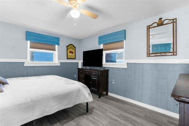 bedroom featuring ceiling fan, wood-type flooring, and multiple windows