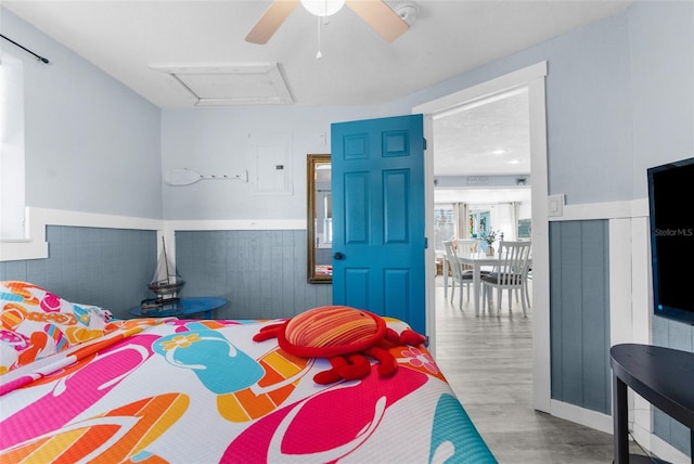 bedroom featuring light wood-type flooring, ceiling fan, and electric panel