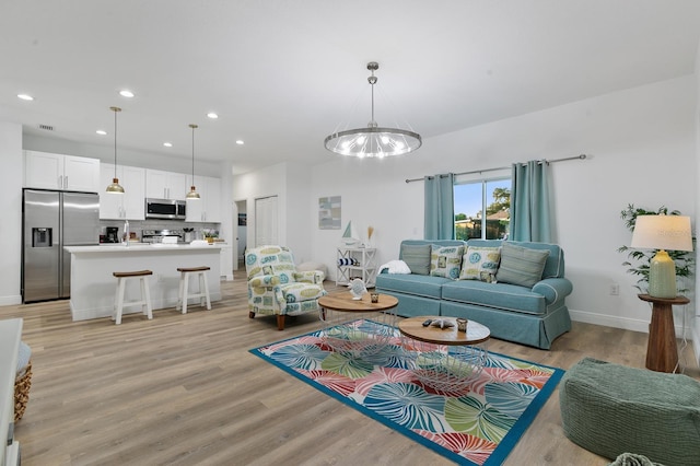 living room with an inviting chandelier and light hardwood / wood-style flooring