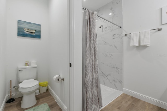 bathroom with toilet, curtained shower, and hardwood / wood-style floors