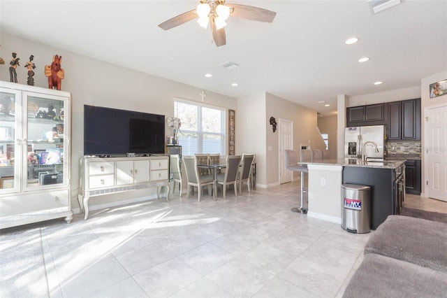 kitchen with dark brown cabinetry, a breakfast bar area, tasteful backsplash, stainless steel fridge with ice dispenser, and a center island with sink