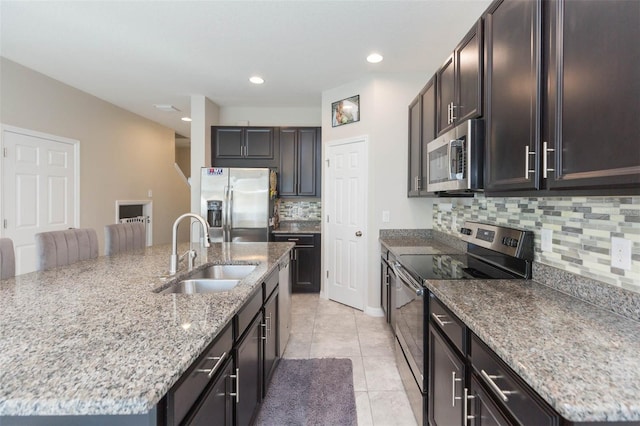 kitchen with sink, backsplash, an island with sink, and appliances with stainless steel finishes