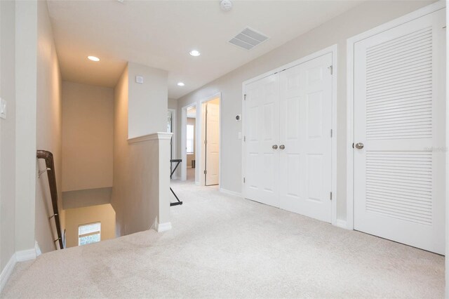 hall with light colored carpet