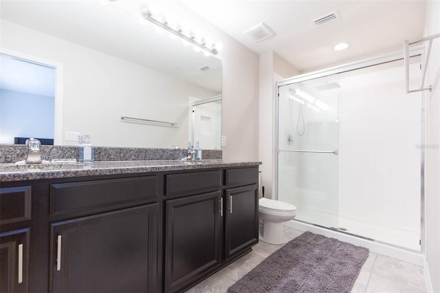 bathroom with a shower with door, vanity, tile patterned floors, and toilet