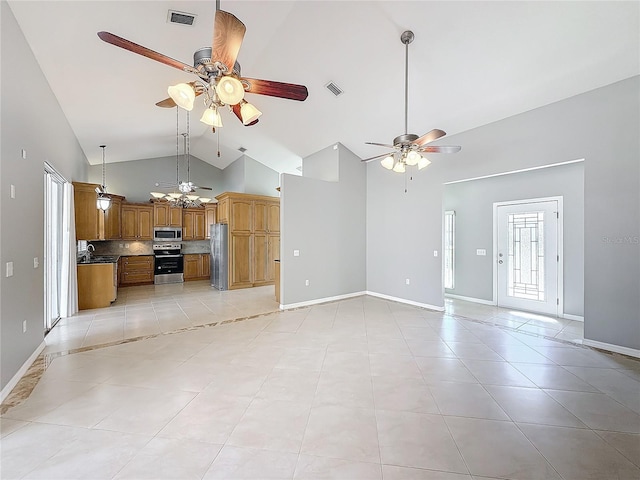 unfurnished living room featuring ceiling fan, sink, light tile patterned floors, and a healthy amount of sunlight