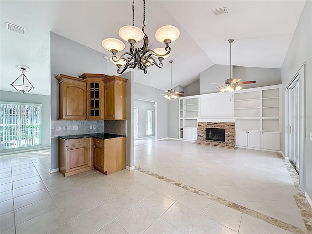 kitchen featuring ceiling fan with notable chandelier, decorative backsplash, light tile patterned floors, and a brick fireplace