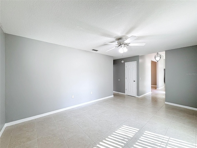 tiled empty room with ceiling fan and a textured ceiling