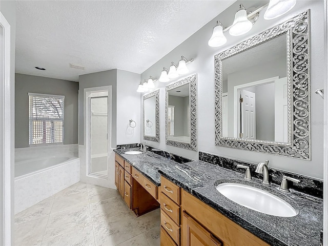 bathroom featuring vanity, a textured ceiling, and tiled tub