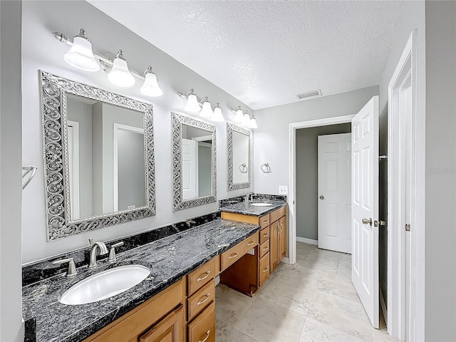 bathroom with vanity, a textured ceiling, and tile patterned flooring