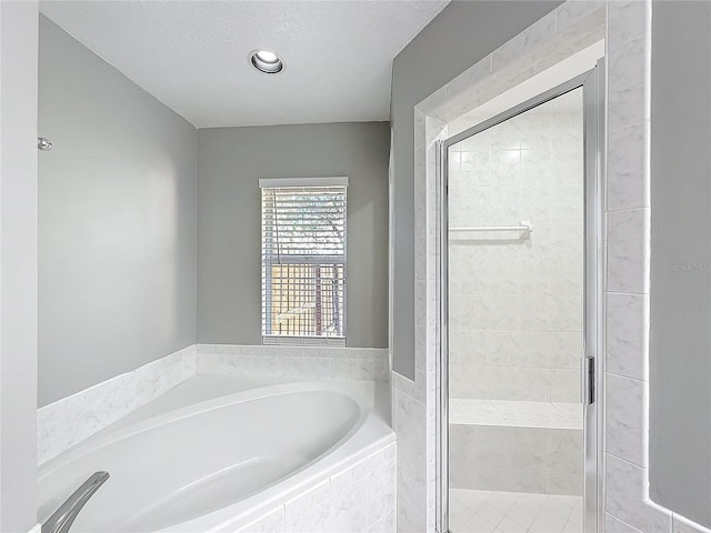 bathroom with a textured ceiling and shower with separate bathtub