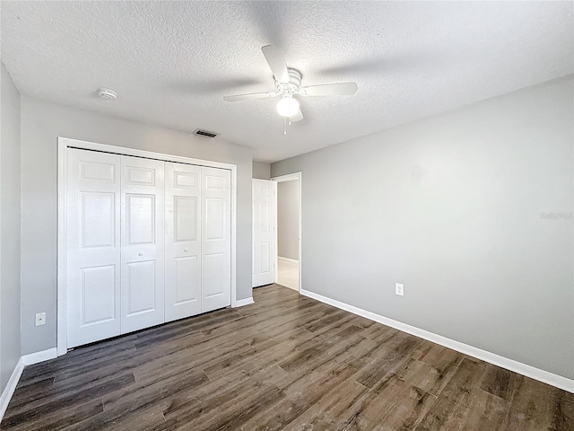 unfurnished bedroom with ceiling fan, dark hardwood / wood-style floors, a textured ceiling, and a closet