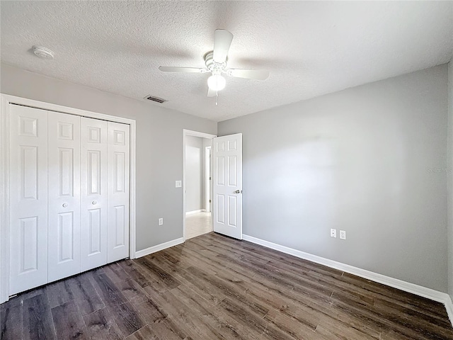 unfurnished bedroom with ceiling fan, a closet, dark wood-type flooring, and a textured ceiling