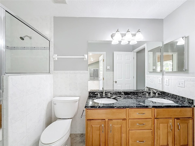 bathroom featuring a textured ceiling, vanity, toilet, and tile walls