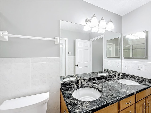 bathroom featuring a textured ceiling, vanity, toilet, and tile walls