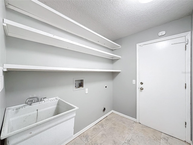 clothes washing area featuring electric dryer hookup, sink, hookup for a washing machine, a textured ceiling, and light tile patterned flooring