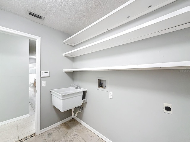 laundry room featuring hookup for a washing machine, a textured ceiling, electric dryer hookup, sink, and light tile patterned flooring