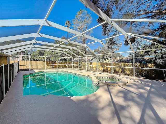 view of swimming pool featuring glass enclosure, a patio area, and an in ground hot tub