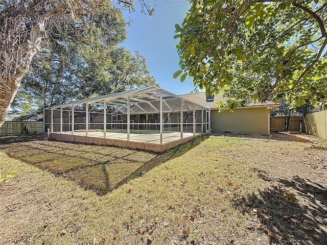 back of house featuring a pool, glass enclosure, and a lawn