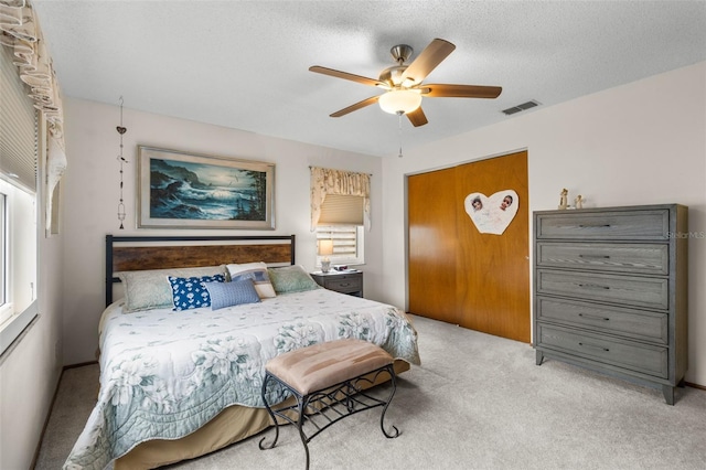 carpeted bedroom featuring ceiling fan and a textured ceiling