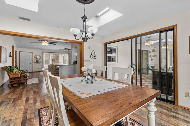 dining space featuring ceiling fan with notable chandelier, dark wood-type flooring, and a skylight